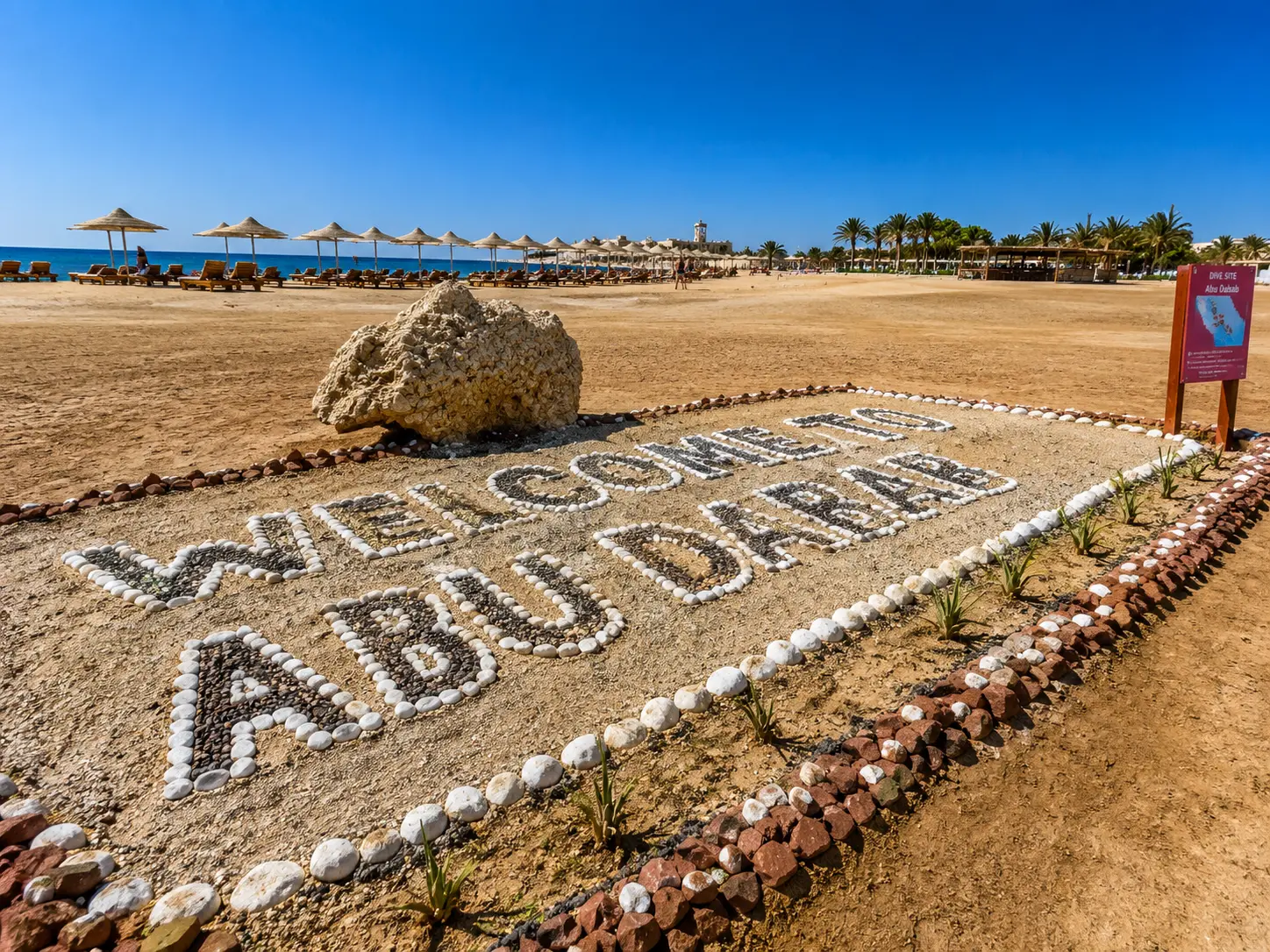 Strandeingang bei Abu Dabab mit Sonnenschirmen und Liegen am Meer