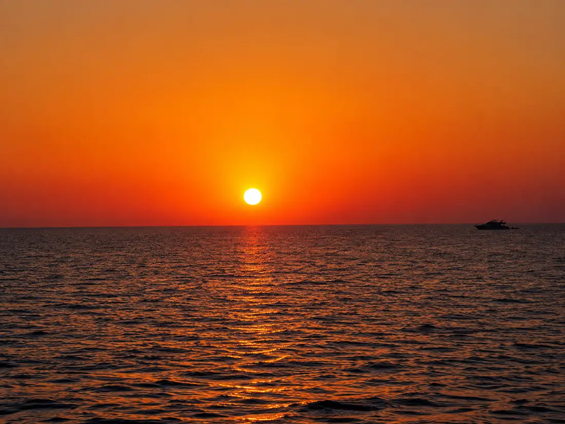 Sonnenuntergang auf dem Roten Meer mit Boot am Horizont